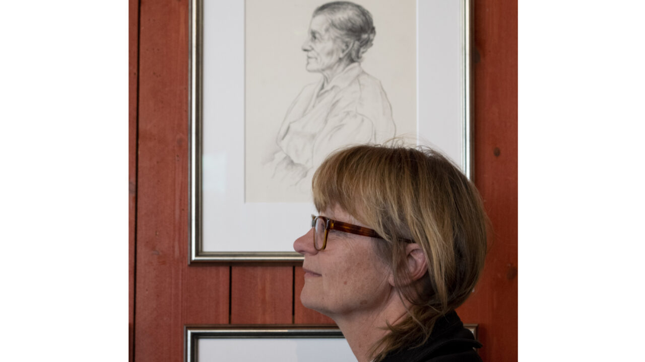 Kvinna i profil bredvid ett tecknad porträtt.