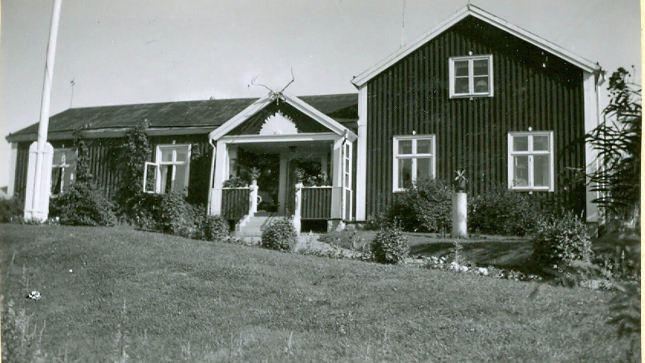 Black and white image of Doktorsgården. A house with white knots and flag windows. The house has two parts, one part has two floors.