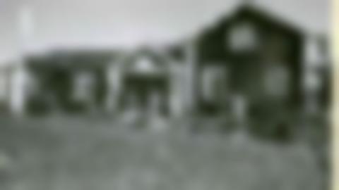 Black and white image of Doktorsgården. A house with white knots and flag windows. The house has two parts, one part has two floors.