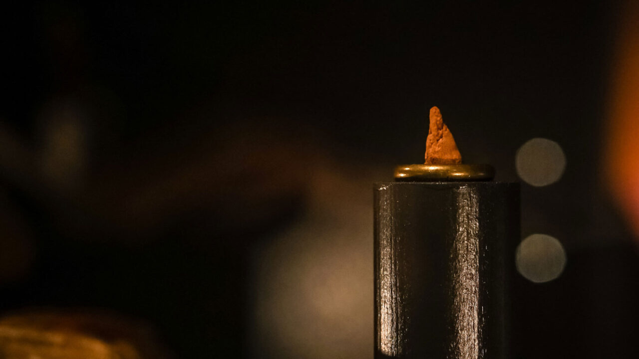 Et litet rött sockertoppsformad föremål står i en mässingsring.