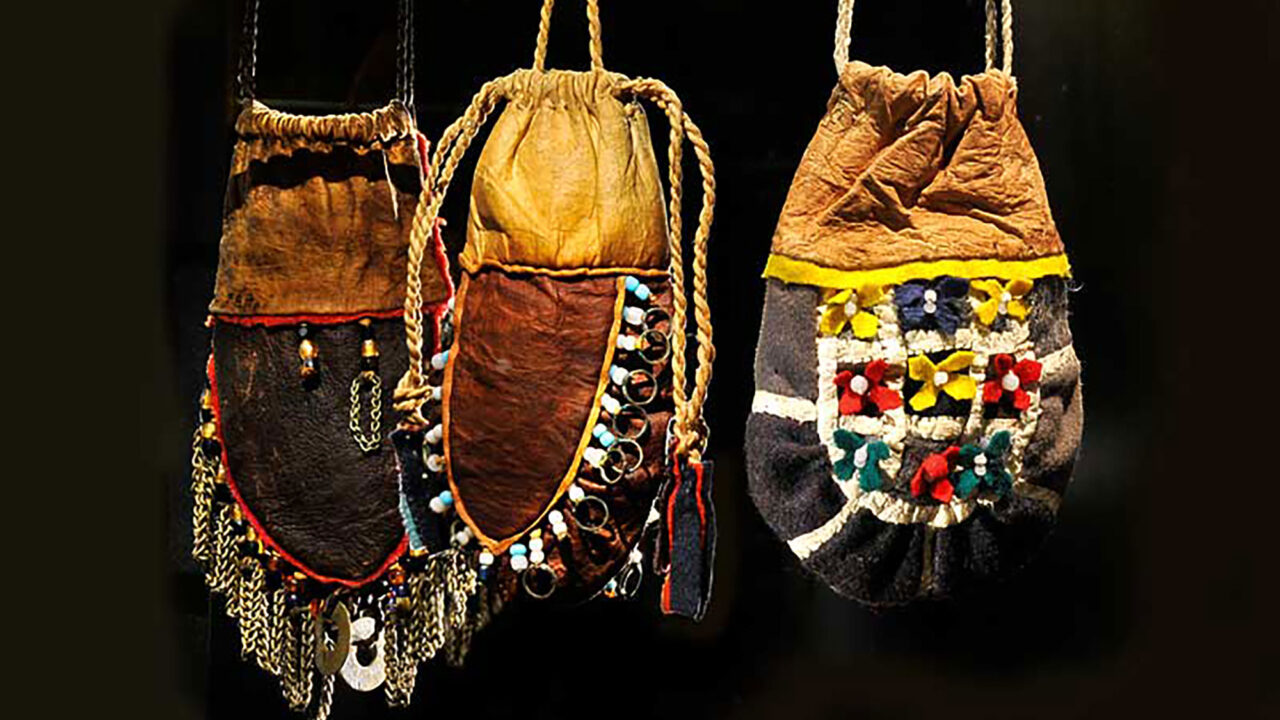 Ur Silvermuseets utställning Mujttalus: Tre påsar i skinn. En även med kläde. Dekorerade med pärlor, kedjor, ringar och små blommor av kläde i rött, gult, blått och grönt.