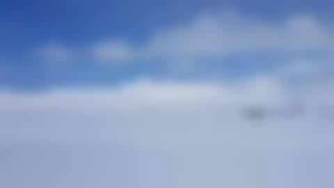 Vitt vinterlandskap på kalfjället, vid skogsgränsen, ljusblå himmel med vita moln. Några träd syns från mitten av bilden och ut mot höger.