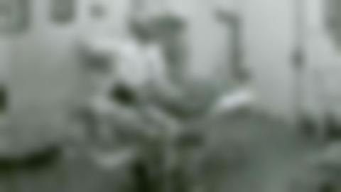 Dr. Einar Wallquist with a patient lying on a bed in a hospital room. Wallquist is wearing a white doctor's coat and black glasses.