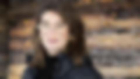 Ung kvinna md mörkt halvlångt hår, bruna ögon och glasögon tittar rakti in i kameran.