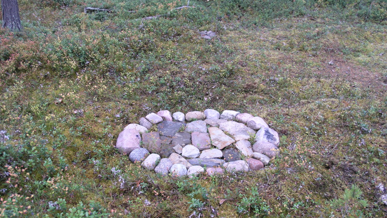 Forest slope in autumn color. In the middle of the picture an oval hearth with paving stones in the middle.