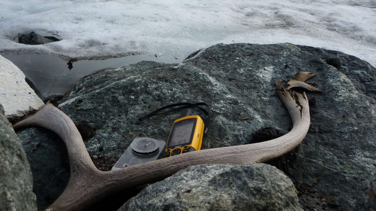 Gammalt, sönderfallande renhorn ligger på en sten tillsammans med en kompass och en GPS.