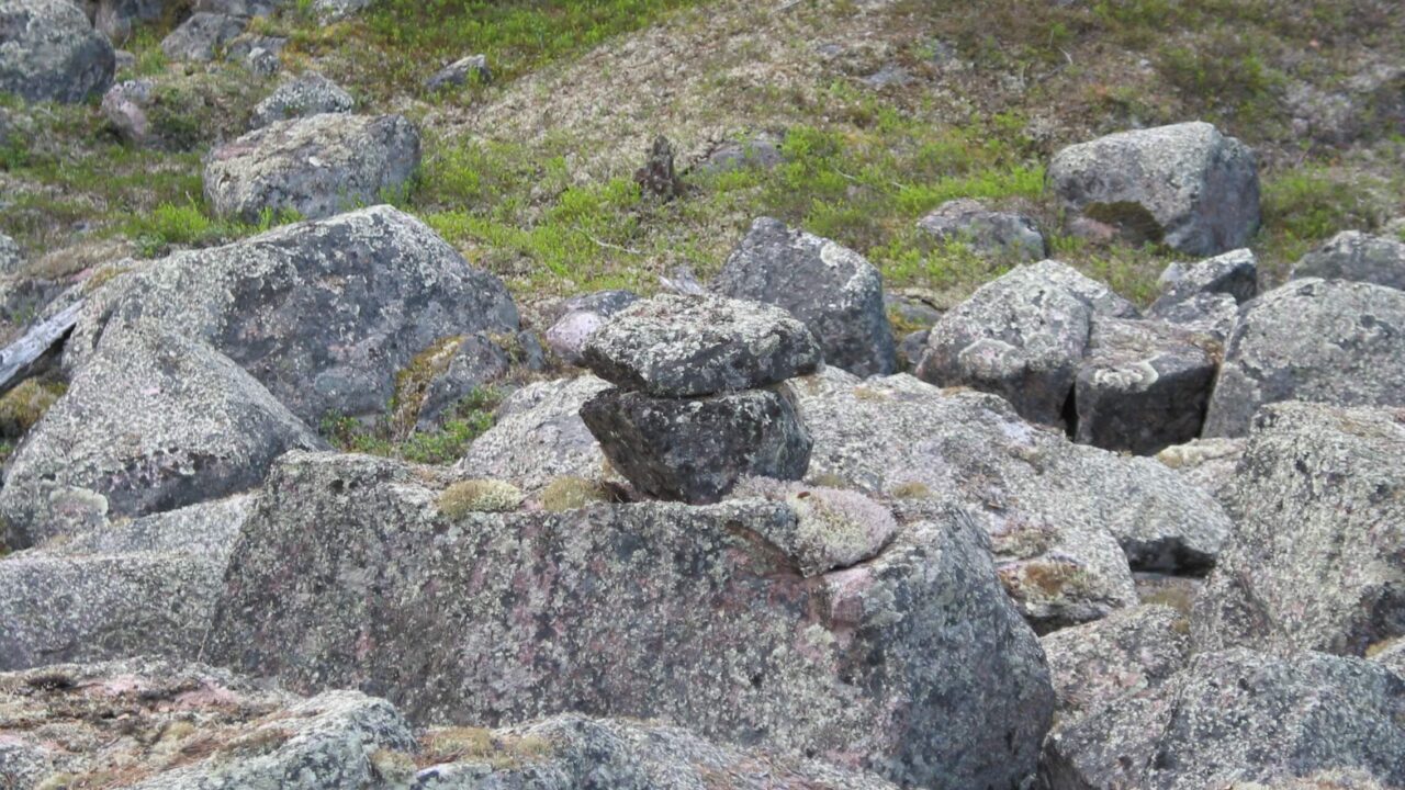 Rocky landscape with a small cairn in the middle. The cairn is difficult to distinguish from the other stones.