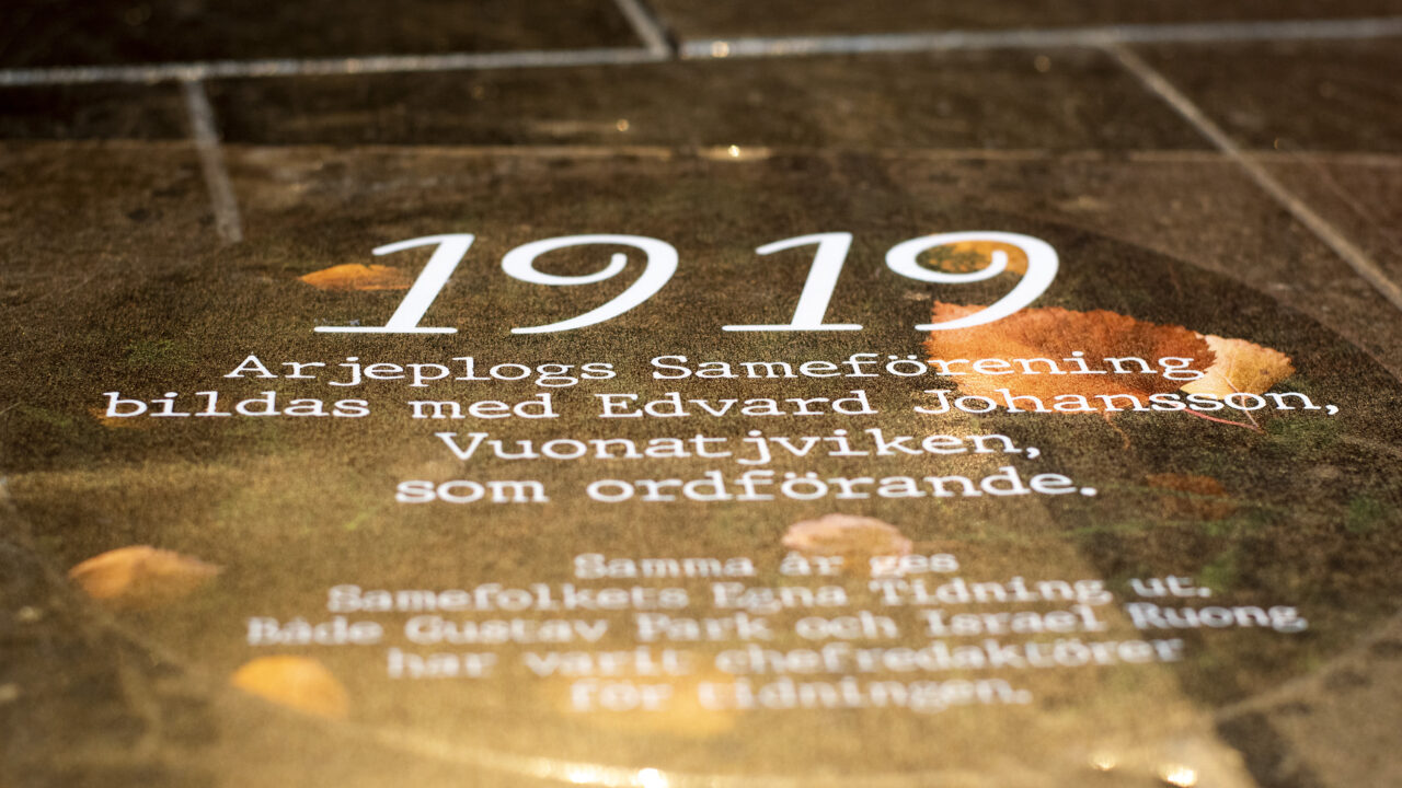 Cirkel med årtal och text på ett golv. I texten står bland annat "1919. Arjeplogs Sameförening bildas med Edvard Johansson, Vuonatjviken, som ordförande".