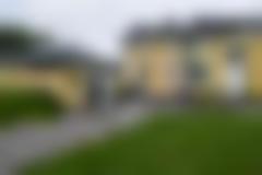 Gul byggnad med grön gräsmatta framför. Grusgång leder fram till bygget.