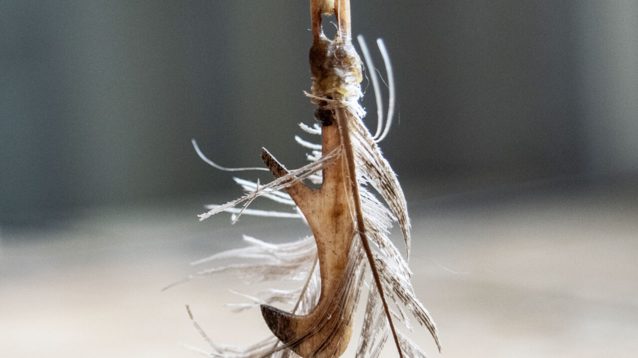 Fiskekrok av horn med fastsurrade fjädrar
