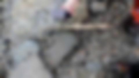 Hand som håller i en telefon för att fota ett pilskaft som ligger bland stenar. Bredvid ligger en tumstock.